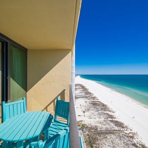 Sunlight sparkles on the coastline as you watch lively beachgoers from your balcony