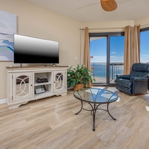 Cozy seating area features a TV and offers a breathtaking view of the gulf from the large windows and balcony access