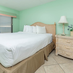 Master bedroom featuring a plush king bed, soft green walls, and coastal-inspired decor