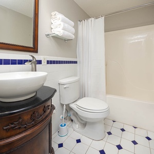 Experience a stylish guest bath featuring a sleek vessel sink, elegant cabinetry, and fresh towels for your convenience