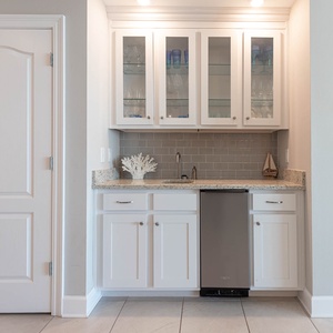 Craft refreshing drinks at the wet bar, with an elegant glass display, as you unwind in your beach retreat