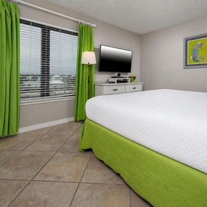 Cozy king guest suite with vibrant green accents and a lovely view through large windows