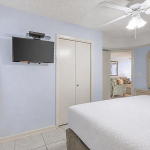 Brightly colored walls complement the king bed, while a wall-mounted TV and mirror enhance this inviting bedroom