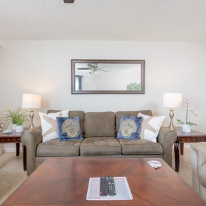 Living room features a brown sofa adorned with decorative pillows, a wooden coffee table, and soft lighting from lamps