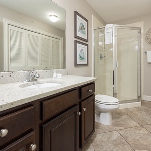 The extra bath features a stylish vanity with dark cabinetry, a walk-in shower, and laundry area with a washer and dryer