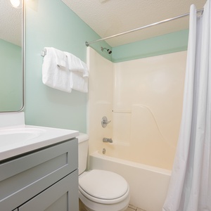 Refresh in this bright bathroom featuring a clean vanity, ample towels, and a shower with a relaxing tub