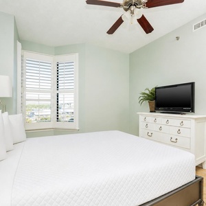 This bedroom features a comfortable bed, a TV for entertainment, and a charming bay window with a lovely view