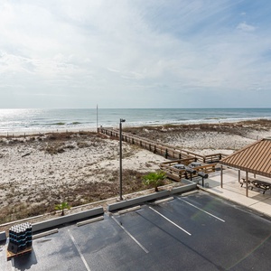 This inviting beachfront view showcases a serene landscape with sandy dunes and a wooden boardwalk leading to the water