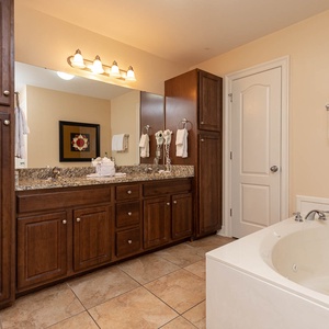 The master bath features elegant cabinetry, a spacious granite countertop, and a relaxing jetted tub for a soothing retreat