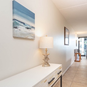 This welcoming hallway features a stylish console table, artwork, and leads to a bright seating area with a lovely view