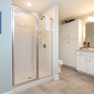 Enjoy a relaxing shower after a day at the beach in this guest bath with stylish cabinetry and spacious vanity