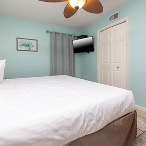 Relax in the serene bedroom featuring a king bed, soft linens, and a wall-mounted TV for entertainment