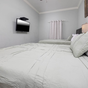 Rest in this inviting guest bedroom with two comfortable queen beds and a mounted TV