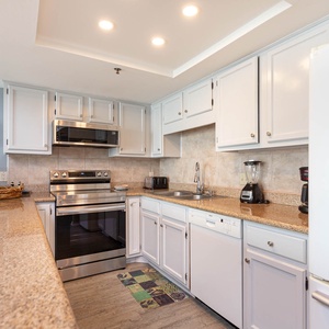 This kitchen features stainless appliances, granite countertops, and a cozy coastal decor, perfect for meal preparation