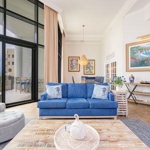 Cozy living area featuring blue sofas, coastal decor, and large windows with a view of the beachfront balcony