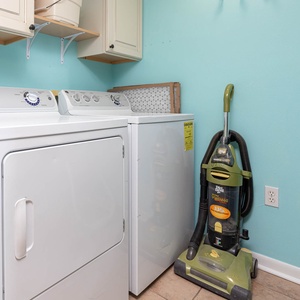 A laundry area features a washer and dryer, complemented by light blue walls and a vacuum cleaner for added convenience