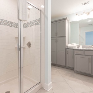 Enjoy a relaxing shower after a day at the beach in this guest bath with stylish accents and fluffy towels