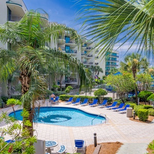 Enjoy the refreshing atmosphere by the pool, embracing the serene sights of palm trees and lush greenery