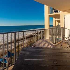 Enjoy a relaxing balcony with a table and chairs, offering a serene view of the beach and tranquil blue waters