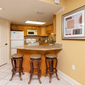 Wood cabinetry complements the granite breakfast bar with seating, creating an inviting space for casual dining