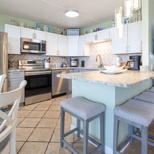 Modern and inviting kitchen featuring stainless appliances, a spacious bar, and coastal decor for a delightful experience