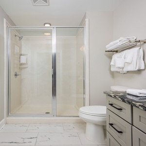 Experience a refreshing shower in this stylish guest bath, featuring elegant countertops and plush towels