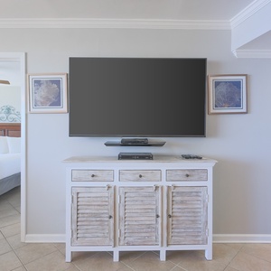 This inviting space features a stylish entertainment center with a large TV, leading to a cozy bedroom beyond