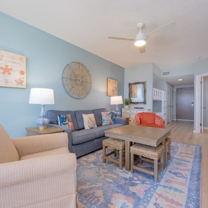 Soft hum of the ceiling fan accompanies your relaxation on the sofa in the living room with coastal decor around you