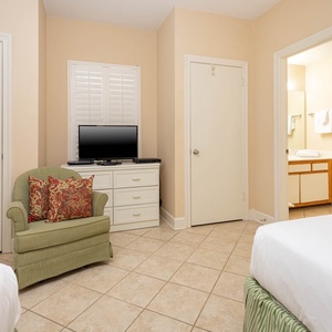 Relax in this cozy guest room featuring double beds, a TV, and a comfortable chair for unwinding