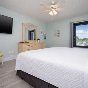 This bedroom features a comfortable bed, a TV for entertainment, and a serene view through the window