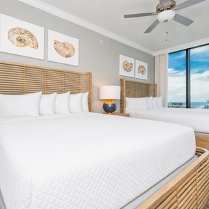 Relax in this guest bedroom featuring two comfortable queen beds, stylish decor, and stunning beach views
