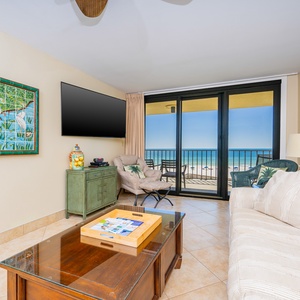 Bright living room featuring a large TV, cozy seating, queen sofa-sleeper, and breathtaking beach views