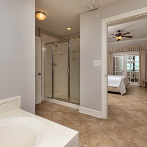 The master bath features a stylish jetted tub, a walk-in glass shower, and a view into the inviting master bedroom suite
