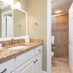 Granite countertops complement the elegant master bath with a walk-in shower and plush towels neatly arranged for guests