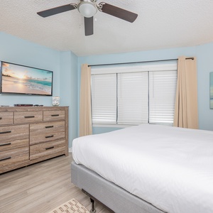 Master bedroom featuring a king bed, stylish dresser, and a wall-mounted TV for relaxation