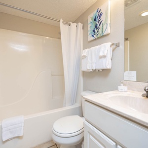 This bathroom features a design with a spacious vanity, fresh towels, and a shower-tub combination for your convenience