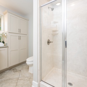 Enjoy a relaxing shower after a day at the beach in this guest bath with stylish accents and fluffy towels