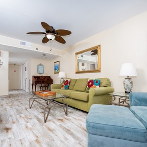Living area featuring a green sofa with colorful pillows, a TV, and stylish decor for a cozy retreat