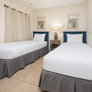 This cozy guest bedroom features two twin beds with charming blue headboards and soft beige decor, perfect for relaxation