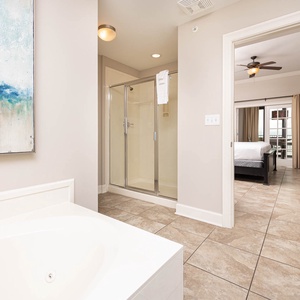 The master bath features a relaxing tub, a glass walk-in shower, and a view into a stylish bedroom with soft lighting