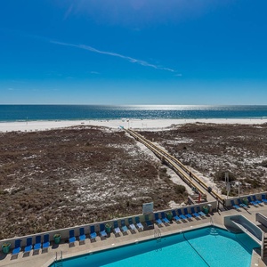 Stunning view of the beach, a winding path leading to the shore, and a pool area with lounge chairs below