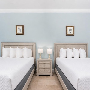 Rest in this guest bedroom featuring two queen beds, soft linens, and charming decor