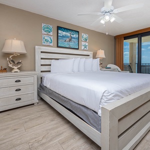 The master bedroom features a plush king bed, coastal decor, and a balcony with breathtaking views of the tranquil waters