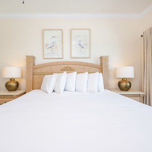 The master bedroom features a king bed with plush linens, stylish lamps, and artwork, creating a restful atmosphere