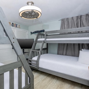 This cozy gust room features two stylish bunk beds, a TV for entertainment, and a nautical decor that enhances the beach vibe