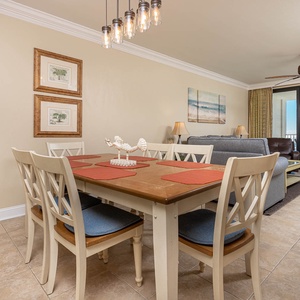 Bright dining area with a wooden table, stylish chairs, and a view of the beachfront through large glass doors