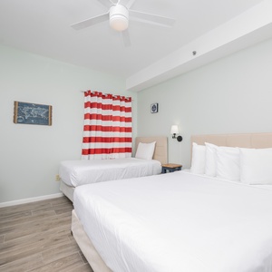 This guest bedroom features a queen and a twin bed, a flat-screen TV, and cheerful striped curtains