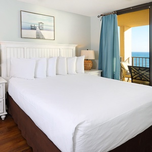 Experience restful nights in this inviting master bedroom with a king bed, stylish decor, and a beachfront view