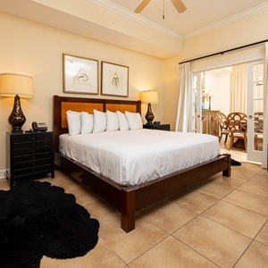 The master bedroom features a king bed, stylish decor, and a cozy seating area, with natural light from the adjacent room