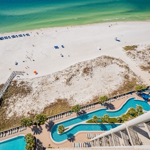 Experience stunning views from the balcony, with a pool area, lazy river, waterslide, and sun loungers below for relaxation